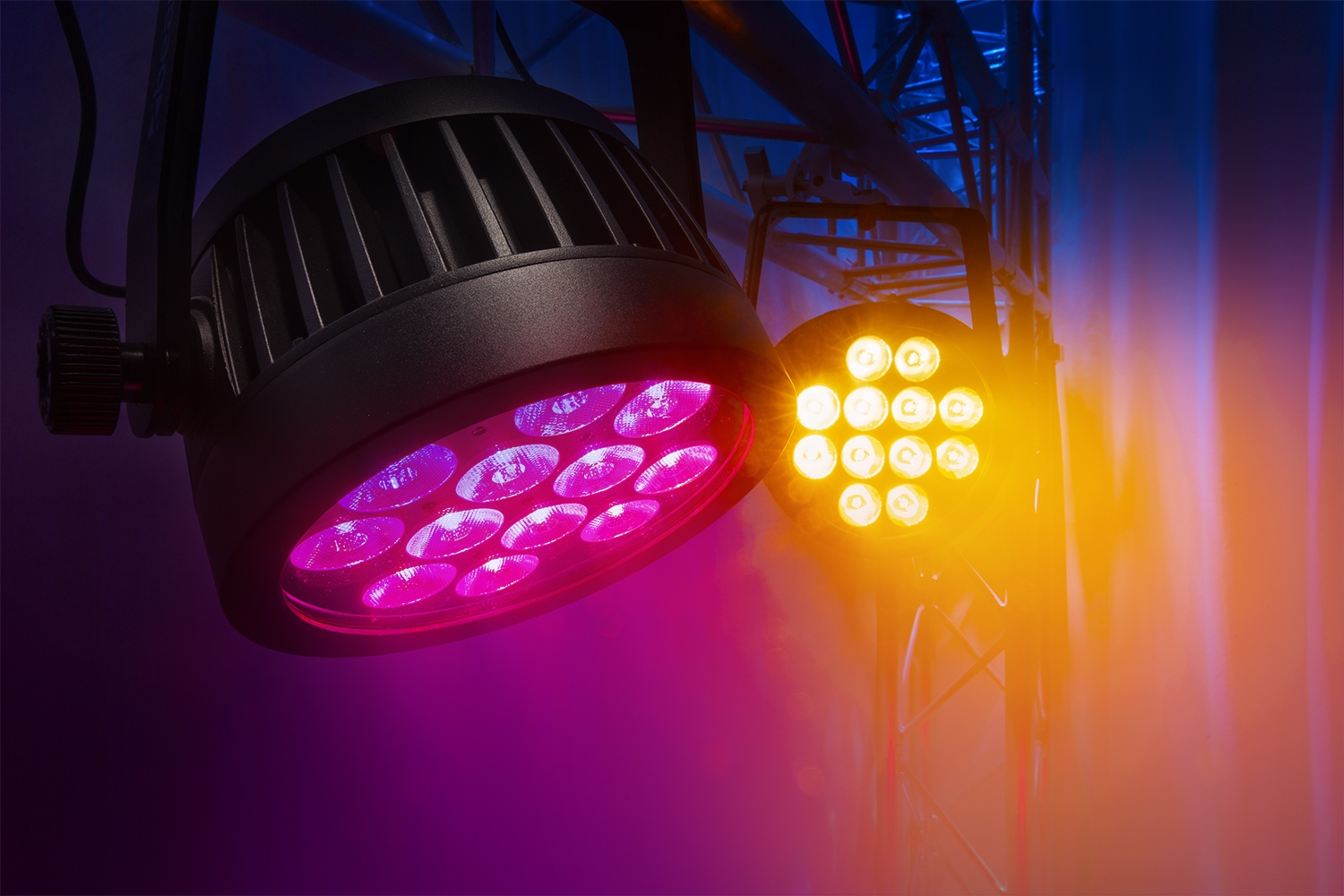 Close-up van twee BeamZ Pro BWA532 LED PAR spots met paarse en geel-oranje verlichting tijdens een lichtshow met rook.
